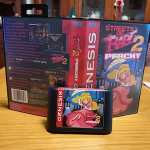 May include: A Sega Genesis game cartridge for Streets of Rage 2: Peachy. The cartridge is black with a colourful image of a pink-haired character in a pink dress. The game case is red and black with the title "Streets of Rage 2: Peachy" in white letters.