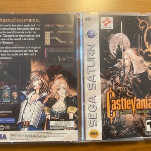 Op de afbeelding: Een Sega Saturn-videospelcase voor Castlevania: Symphony of the Night. De voorkant van de case toont een zwart-witte illustratie van Alucard, een vampierjager, die in een donker kasteel staat. De achterkant van de case toont een kleurrijke illustratie van Alucard en een vrouwelijk personage.