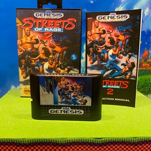 May include: A Sega Genesis video game cartridge and instruction manual for Streets of Rage 2. The cartridge is black with a Sega Genesis logo and the game title. The instruction manual is blue and white with the game title and a picture of characters from the game.