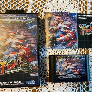 May include: A boxed Sega Mega Drive video game cartridge, "Final Fight Christmas Edition." The box, cartridge, and manual feature festive artwork of characters in Santa hats. The game cartridge is black.