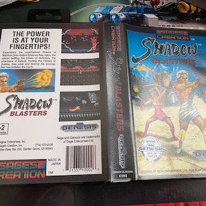 Könnte beinhalten: Sega Genesis-Spielkassette für Shadow Blasters. Das Spiel wurde von Sages Creation entwickelt und zeigt eine Schwarzweißillustration eines Kriegers, der ein flammendes Schwert hält. Der Text "Shadow Blasters" ist in Weiß auf schwarzem Hintergrund gedruckt.
