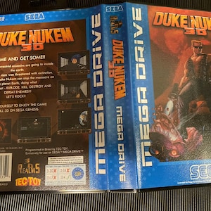 Op de afbeelding: Een Sega Genesis-spelcartridge voor Duke Nukem 3D. De voorkant van de cartridge toont een 3D-weergave van Duke Nukem, een gespierde man met een geschoren hoofd, die een pistool vasthoudt. De achterkant van de cartridge bevat een beschrijving van het spel en een beoordelingssysteem.