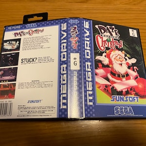 May include: Sega Mega Drive game cartridge for the game "Daze Before Christmas". The cartridge is blue and white with a picture of Santa Claus on the front. The back of the cartridge has a description of the game and a warning.
