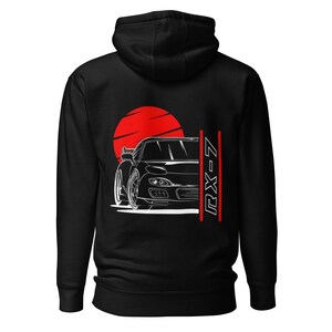 May include: Black hoodie featuring a white graphic of a black car with a red sun rising behind it. The text "RX-7" is printed vertically on the right side of the car.