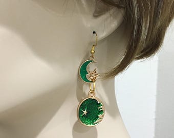 May include: Gold dangle earrings with green enamel crescent moons and stars. The crescent moon charms are connected by a gold chain.