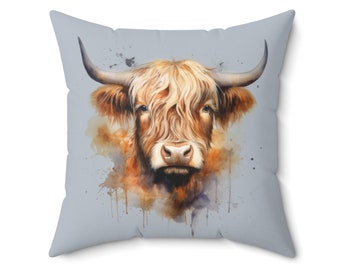 May include: A watercolor painting of a Highland cow with a light brown and orange coat. The cow is looking directly at the viewer with a soft expression. The background is a light blue with watercolor splatters.
