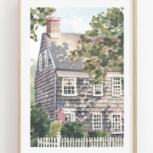 May include: A watercolor painting of a gray clapboard house with white trim and windows. The house has a white picket fence in front of it and a small American flag hanging on the side. The house is surrounded by green trees and bushes.