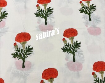 May include: White fabric with a repeating pattern of red flowers with green leaves and stems. The flowers have a textured appearance. The text "sabira's" is printed on the fabric.