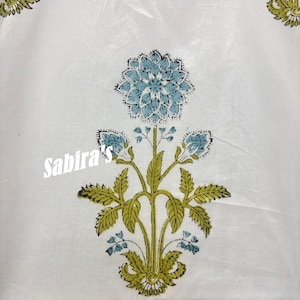 Pu&ograve; includere: Tessuto bianco con un motivo floreale blu e verde. Il design presenta un grande fiore centrale e boccioli pi&ugrave; piccoli con foglie dettagliate. Il testo "Sabira's" &egrave; stampato in bianco sull'immagine.