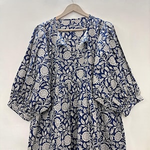 Könnte beinhalten: Ein blaues Kleid mit weißem Blumenmuster, V-Ausschnitt und 3/4-Ärmeln. Das Kleid hat einen gerafften Rock und eine lockere Passform.