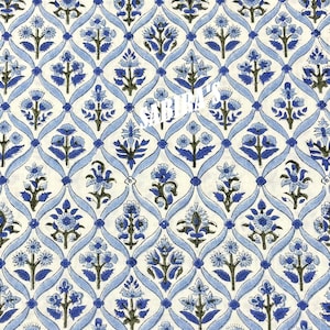 May include: A repeating pattern of blue floral designs and light blue ribbons on a cream background. The floral elements are detailed with dark green accents, creating a symmetrical and decorative textile design.