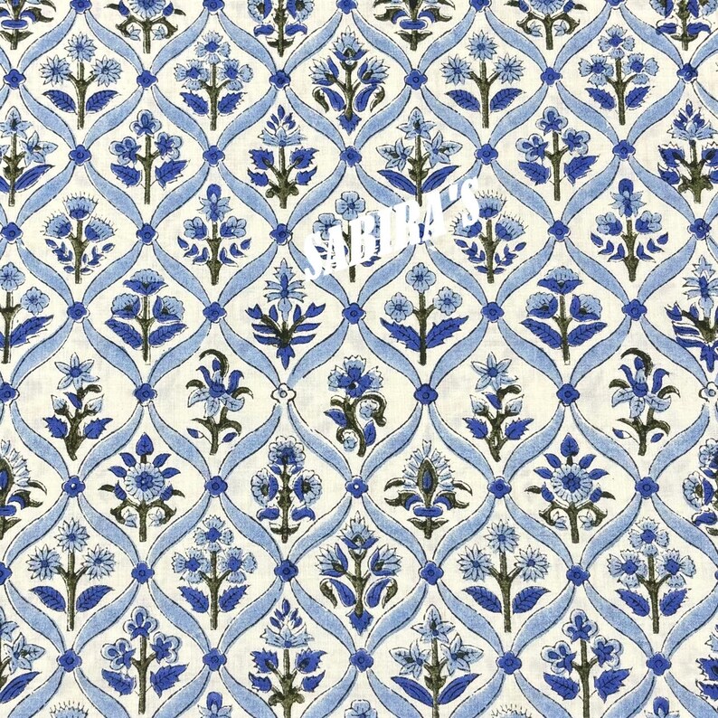 May include: A repeating pattern of blue floral designs and light blue ribbons on a cream background. The floral elements are detailed with dark green accents, creating a symmetrical and decorative textile design.
