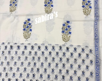 May include: White fabric with a blue floral pattern. The design features large blue flower bouquets and a smaller repeating pattern. The text "sabira's" is printed on the fabric. A blue border with a floral design is on the right side.