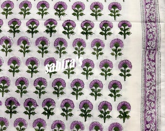 May include: White fabric with a repeating pattern of purple flowers and green stems. The flowers have a detailed, layered petal design. A decorative border with floral motifs runs along the right edge. The text "sabra's" is visible in the center.