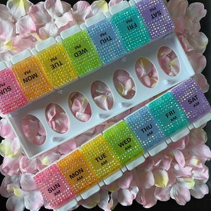 Puede incluir: Un organizador de pastillas arco&iacute;ris con siete compartimentos para cada d&iacute;a de la semana. Los compartimentos est&aacute;n etiquetados con los d&iacute;as de la semana y AM o PM. El organizador est&aacute; decorado con diamantes de imitaci&oacute;n.