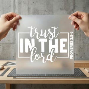 May include: A translucent sheet with the words "trust IN THE Lord" in white script and block letters. The text is enclosed in a white rectangular border. The scripture reference "PROVERBS 3:5-6" is printed vertically on the right side.