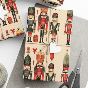 May include: A set of three gift wrapping papers featuring a vintage-inspired design of nutcracker soldiers in red, blue, and green uniforms. The papers are printed on a cream background with a subtle sparkle.