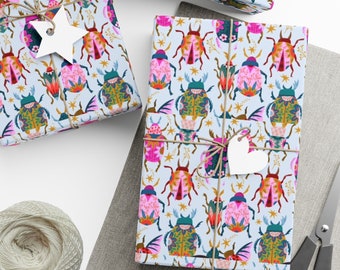 May include: Three gift boxes wrapped in blue and white patterned paper with colorful bugs and stars. The boxes are tied with twine and decorated with white paper hearts and stars.