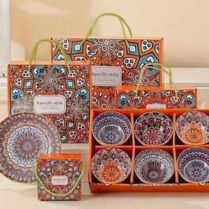 Peut inclure: Ensemble de six bols en céramique colorés avec des motifs de mandala complexes dans des tons d'orange, de bleu et de blanc. Les bols sont emballés dans une boîte avec un motif assorti et les mots "Specific style" imprimés sur le devant.