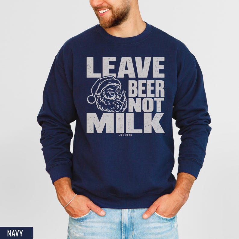 A man wearing a navy blue crewneck sweatshirt with white text that reads LEAVE BEER NOT MILK and a graphic of Santa drinking a beer.
