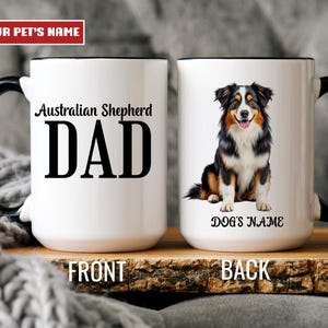 May include: White ceramic mug with a black handle and rim. The front of the mug reads "Australian Shepherd DAD" in black text. The back features a color illustration of an Australian Shepherd dog with the text "DOG'S NAME".
