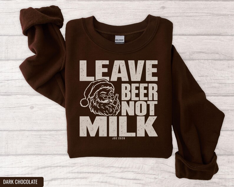 Dark brown crewneck sweatshirt featuring a graphic of winking Santa drinking beer with text Leave Beer Not Milk.