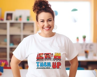 May include: White t-shirt with a colorful cartoon train and the text "Bringing Them Up Deuteronomy 32:10"