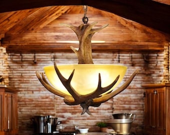 May include: A rustic chandelier made from antlers and a frosted glass shade. The chandelier is hanging from a wooden ceiling in a kitchen.