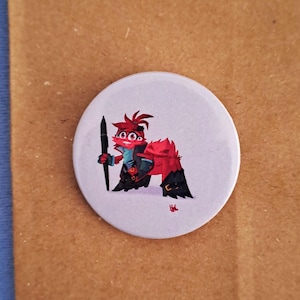 Op de afbeelding: Een rood en zwart cartoonfiguur met drie ogen dat een penseel vasthoudt. Het figuur staat op een witte achtergrond.