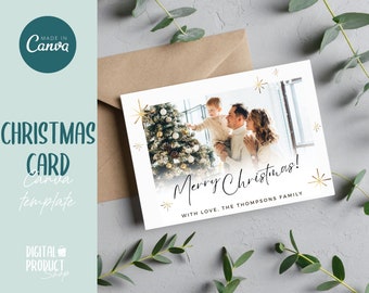 Könnte beinhalten: Eine weiße Weihnachtskarte mit einem Foto einer Familie, die vor einem geschmückten Weihnachtsbaum steht. Der Text "Frohe Weihnachten!" ist in schwarzer Kursivschrift mit goldenen Sternen geschrieben. Der Text "Mit Liebe, Die Familie Thompson" ist in Schwarz unter dem Gruß geschrieben.