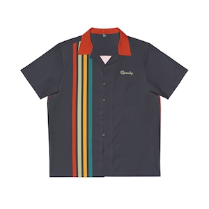 Op de afbeelding: Een donkerblauw shirt met korte mouwen en een retro-ontwerp. Het shirt heeft een meerkleurige streep aan de linkerkant en een zakje op de linkerborst met het woord "Speedy" in het groen geborduurd.
