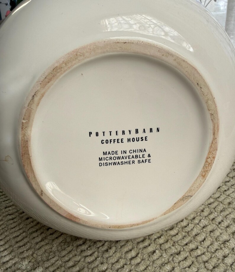 May include: Off-white ceramic serving bowl with the text "POTTERY BARN COFFEE HOUSE" and "MADE IN CHINA MICROWAVEABLE & DISHWASHER SAFE" on the base. The bowl is microwave and dishwasher safe.
