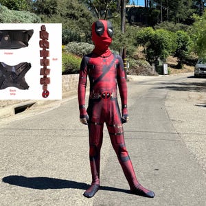 May include: A child dressed as Deadpool, a superhero character, wearing a red and black costume with a mask. The costume has a belt with pouches and a black strap across the chest.