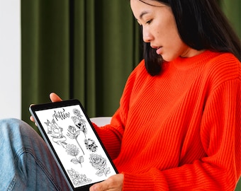 May include: A person wearing blue jeans and a red sweater is looking at a tablet screen. The screen displays a digital drawing of various tattoo designs, including flowers, leaves, and a skull. The text "Tattoo" is written at the top of the screen.