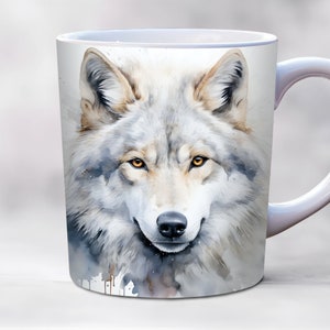 Puede incluir: Taza de cerámica blanca con una ilustración de acuarela de la cara de un lobo. El lobo tiene ojos marrones y un pelaje blanco y gris.