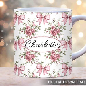 Op de afbeelding: Witte keramische mok met een roze bloemenpatroon en roze strikken. De mok heeft de naam "Charlotte" in een cursief schrift op de voorkant.