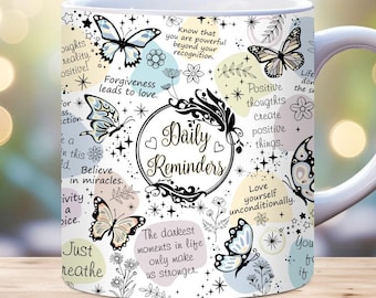 May include: White ceramic mug with a black and white design featuring butterflies, flowers, and inspirational quotes. The quotes include "Daily Reminders", "Forgiveness leads to love", "Believe in miracles", "Love yourself unconditionally", and "The darkest moments in life only make us stronger".