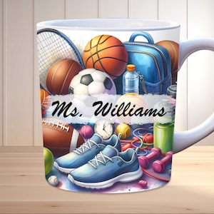 May include: White ceramic mug with a colorful design featuring sports equipment like a basketball, soccer ball, tennis racket, and running shoes. The mug has the text "Ms. Williams" on it.