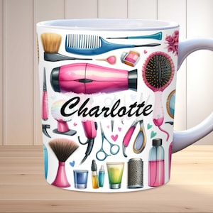 May include: White ceramic mug decorated with a watercolour design of hairdressing tools, including a pink hairdryer, brushes, and scissors. The name "Charlotte" is written in black script. The mug has a white handle.