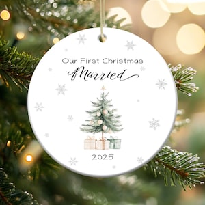 May include: White round Christmas ornament with a green watercolor Christmas tree, presents, and the text "Our First Christmas Married 2025".