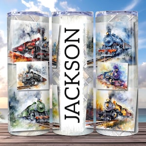 以下が含まれることがあります： 赤、黒、緑、青の色合いのヴィンテージ列車を描いた水彩イラストが特徴のステンレス鋼タンブラー。「JACKSON」という名前がタンブラーの中央に太字の黒い文字で縦に印刷されています。