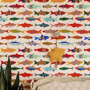 Könnte beinhalten: Tapete mit einem sich wiederholenden Muster aus bunten Fischen auf weißem Hintergrund. Die Fischmuster variieren in Farben wie Rot, Blau, Gelb und Grün. Ein gelbes sternförmiges Mobile hängt vor der Tapete.