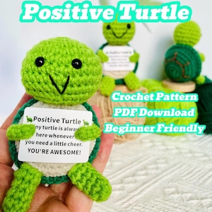 May include: A handmade green crochet turtle with a white belly and a small sign that reads "Positive Turtle." The sign says "You're Awesome!" and the text "Crochet Pattern PDF Download Beginner Friendly" is also visible.