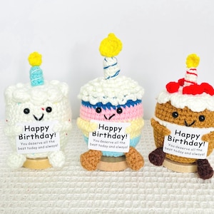 May include: Three handmade crochet birthday cake decorations. Each cake has a smiling face, a candle, and a sign that reads "Happy Birthday! You deserve all the best today and always!" The cakes are white, brown, and multi-colored.
