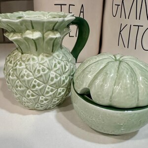 Może przedstawiać: Zielony ceramiczny dzbanek w kształcie ananasa i zielona ceramiczna cukiernica w kształcie limonki z pokrywką.
