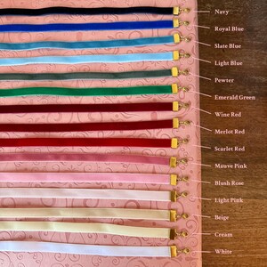 Op de afbeelding: Een verzameling fluwelen lintchokers in verschillende kleuren, waaronder marineblauw, koningsblauw, leisteenblauw, lichtblauw, pewter, smaragdgroen, wijnrood, merlotrood, scharlakenrood, mauve roze, blush roze, lichtroze, beige, cr&egrave;me en wit. Elke choker heeft een goudkleurige sluiting.