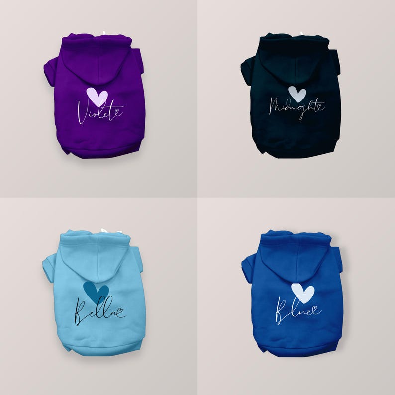 May include: Four pet hoodies in purple, black, light blue, and royal blue. Each hoodie features a hood, short sleeves, and a white heart graphic above cursive text reading Violette, Midnight, Bella, or Blue with a small heart accent.