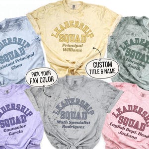 May include: Six tie-dye t-shirts with the text "Leadership Squad" in a retro font. Each shirt has a different job title and name printed below the text. The shirts are in various colors, including blue, yellow, gray, purple, and pink.