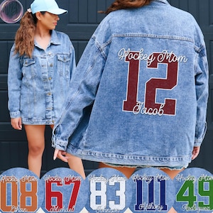 May include: A light blue denim jacket featuring the text "Hockey Mom", the number 12, and the name "Jacob" on the back. The jacket has a button-up front and pockets. Circular designs with different numbers and names are at the bottom.