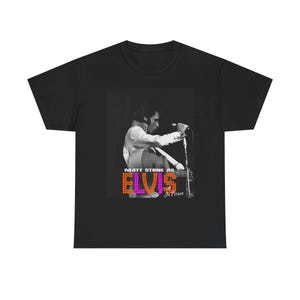 May include: Black t-shirt featuring a black and white image of a person playing a guitar and singing into a microphone. The image has the text "MATT STONE AS ELVIS In Person" in orange and purple pixelated font.